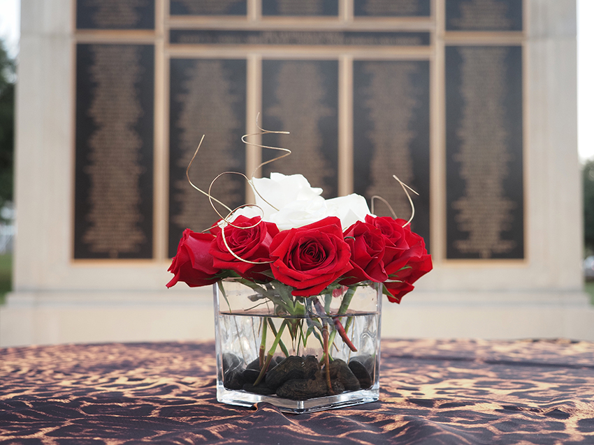 Flowers on table in front of Wall of Honor.