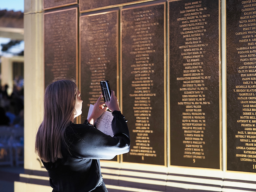 Woman taking picture of wall of honor.