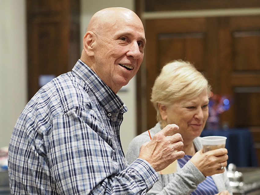 Two people holding their drinks and smiling.