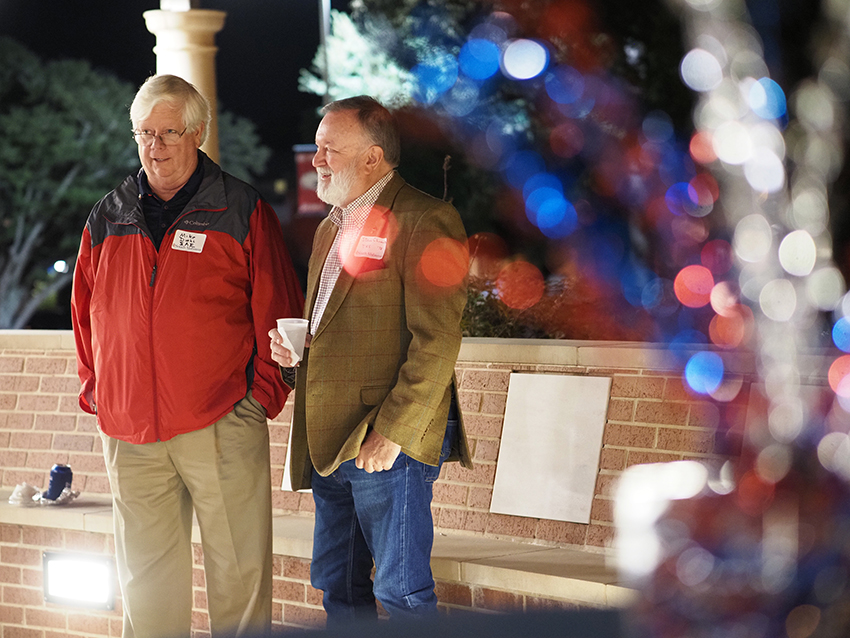 Two men at greek reunion talking outside.