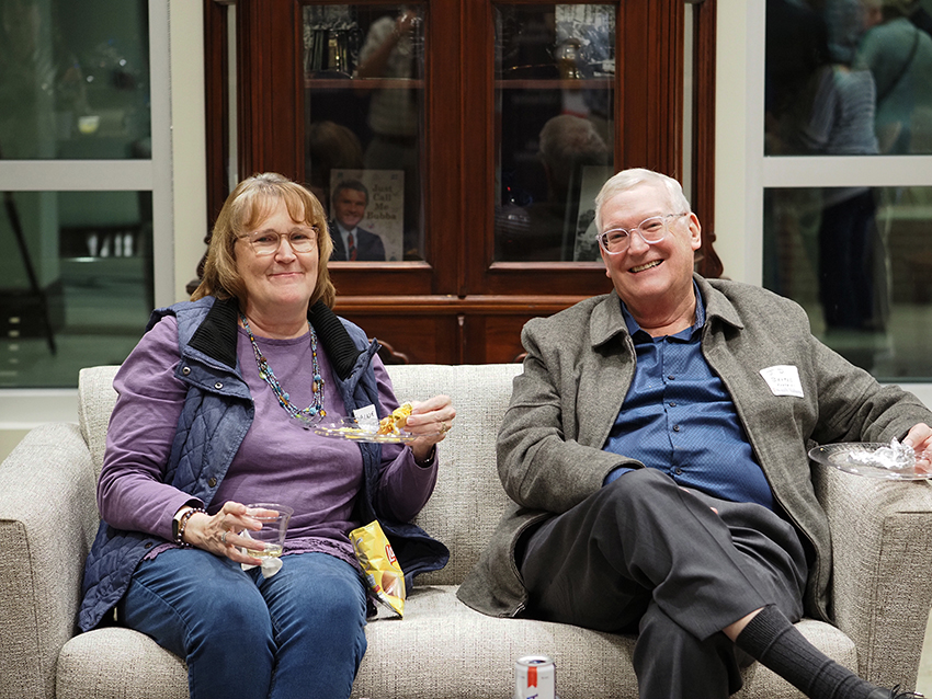 A couple sitting together on couch at Greek reunion.