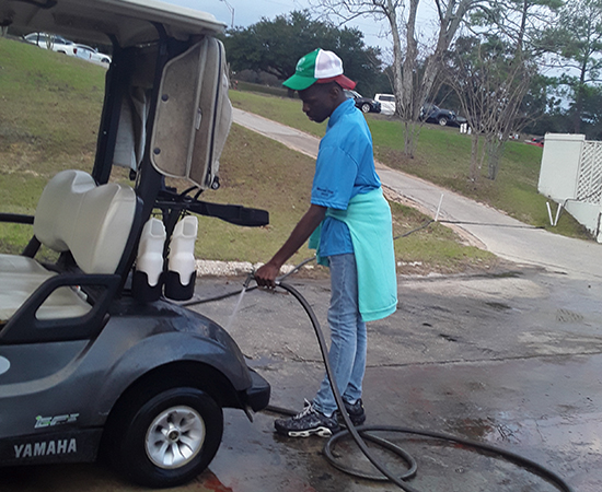 Aaron cleaning golf cart at Heron Laes.