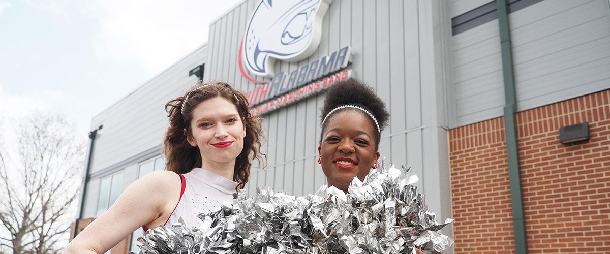 Front of the JMB complex with two cheerleaders.