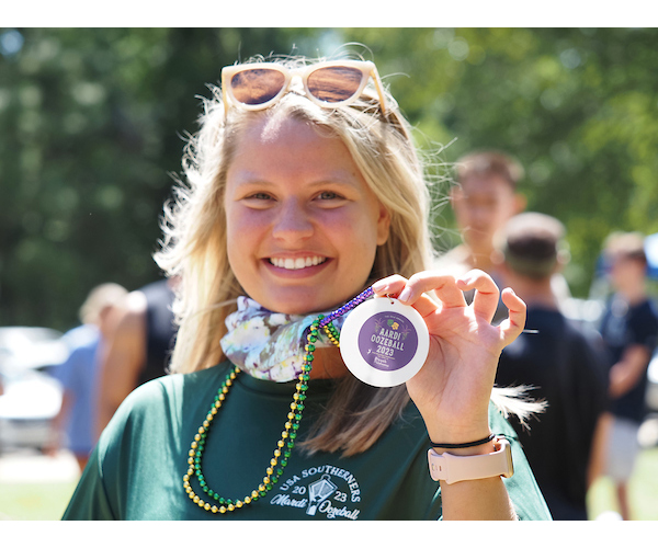 Student holing up necklace smiling.