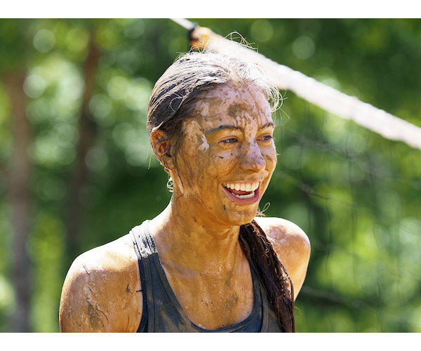 Student with braid covered in mud smiling.