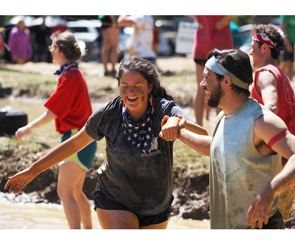 Students laughing as they make their way through the mud during oozeball.