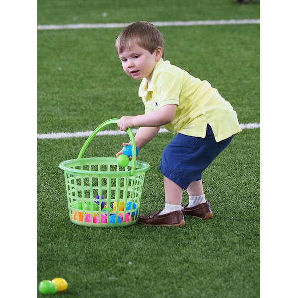 boy setting a basket down to pick up several Easter eggs