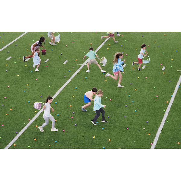 several children running through a field with many eggs