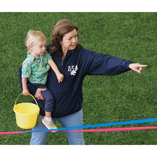 parent pointing to eggs on the field carrying the child to retrieve such eggs