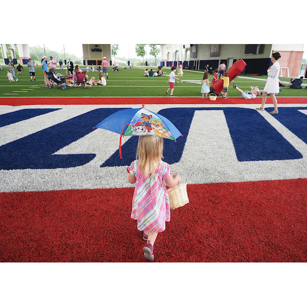 A girl walking across the field with an umbrella