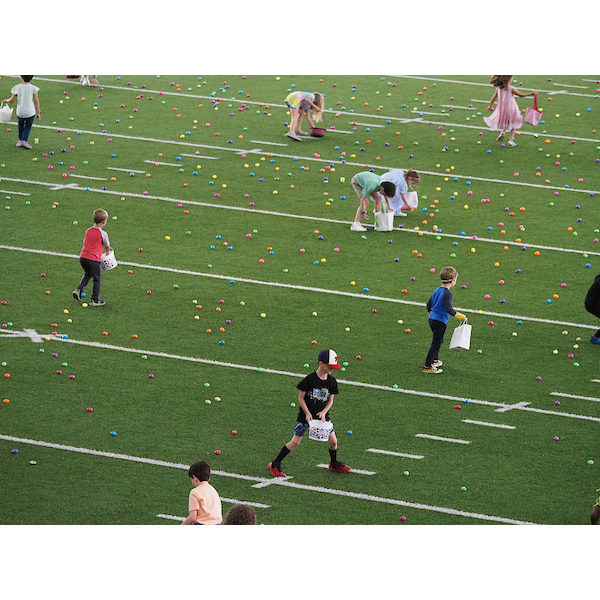 several children running through a field with many eggs
