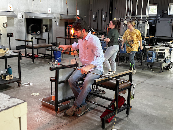 man working on a glass working station, putting the last touches on a new piece