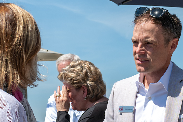 Man and woman talking at alumni event outside.