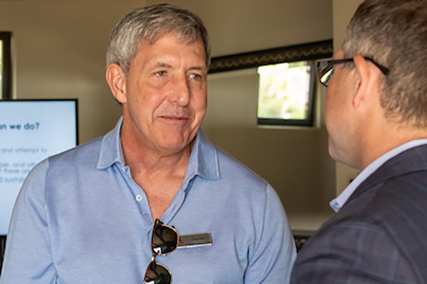 Man in blue shirt talking to man in suit at alumni event.