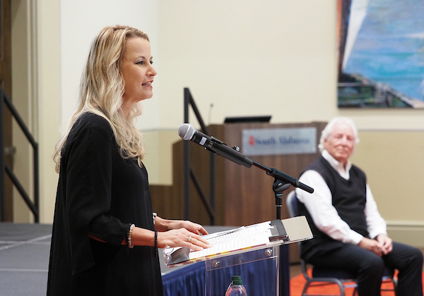 Speaker presenting to the audience, Dr Hayes in the background