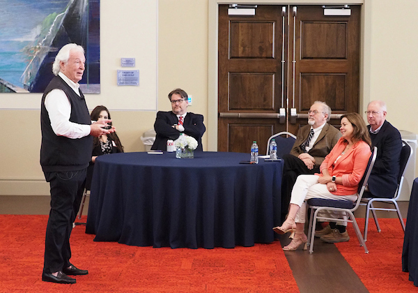 Richard Hayes speaking next to a table of attendees