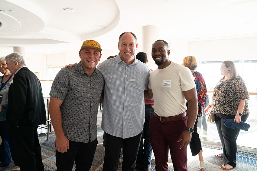 Three alumni at event smiling.