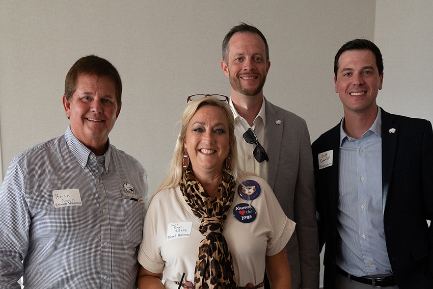 Four alumni at event smiling.