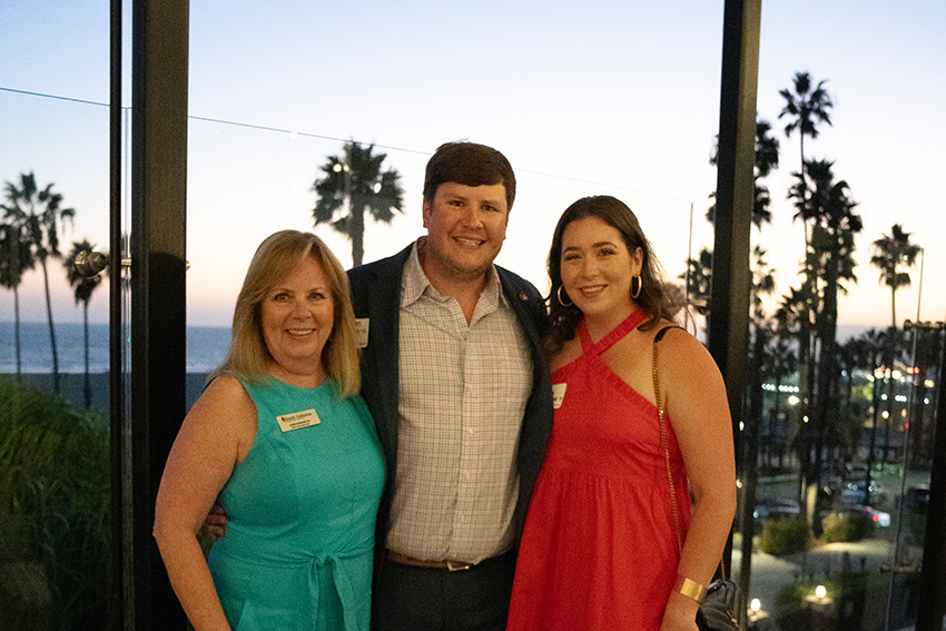 Alumni with Karen Edwards with palm trees in the background.