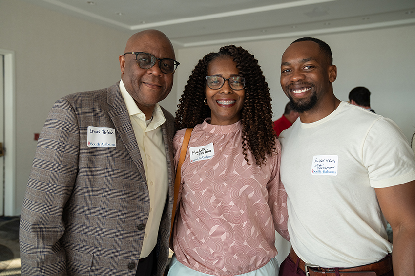 Three alumni smiling at Santa Monica Event.