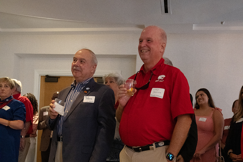 Two alumni holding drinks at event.