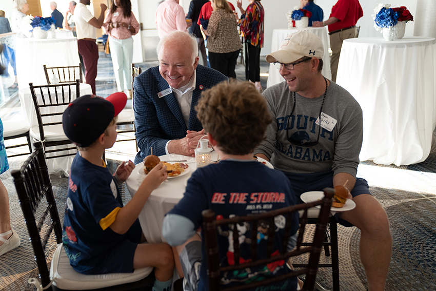 President Bonner speaking to little boys with their father at event.