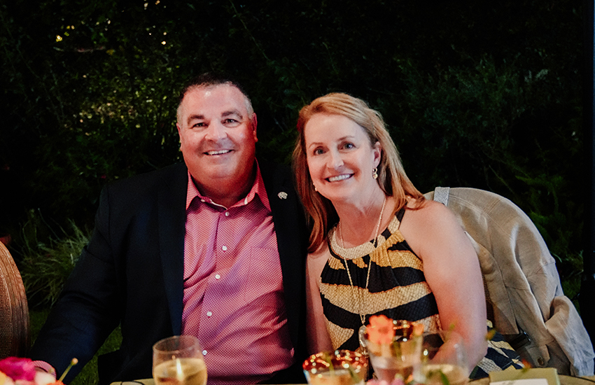 Couple sitting at dinner table smiling.