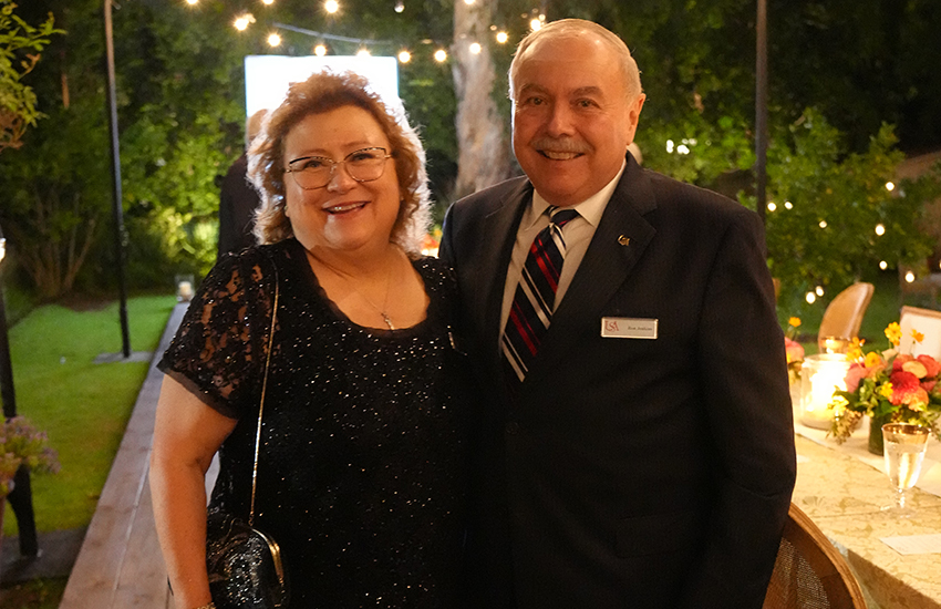 Couple standing together at event with table in background.