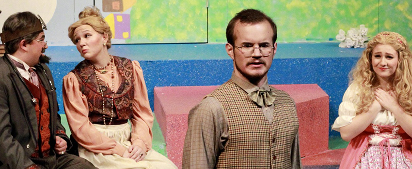 USA Students acting on stage in a play with men wearing vests and women in dresses.