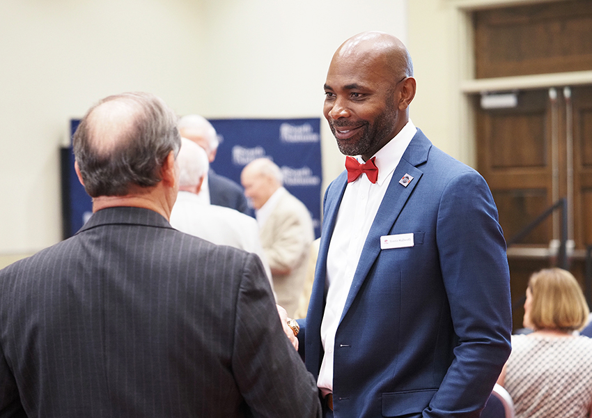 Man in bowtie and suit listening to someone talk.