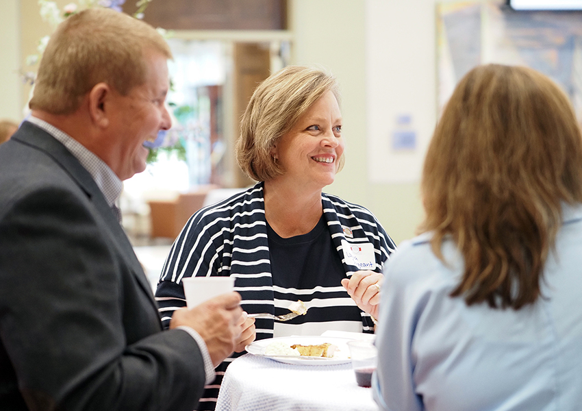 Three people talking around table.