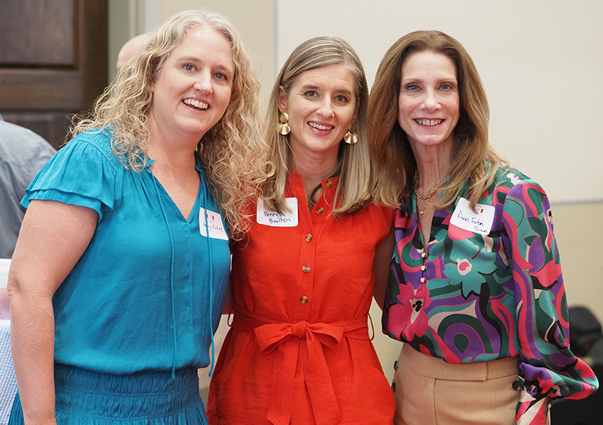 Three female alumni smiling at camera.