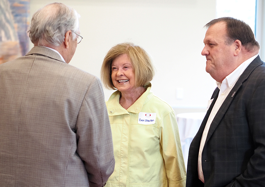 Geri Moulton smiling with two alumni.