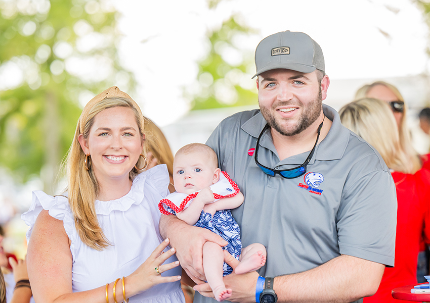 Two alumni and a child smiling.