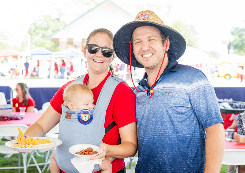 Two alumni and a child smiling.