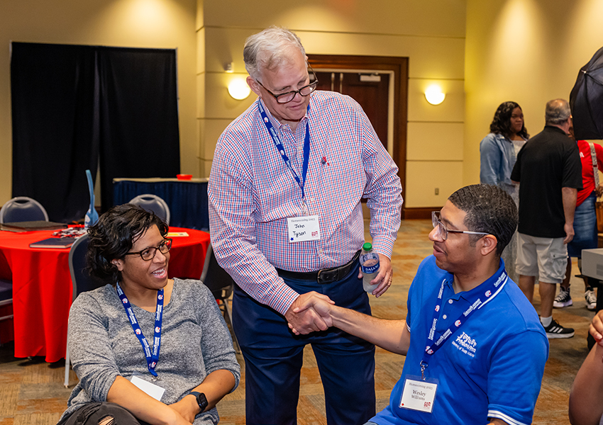 Three alumni greeting each other.