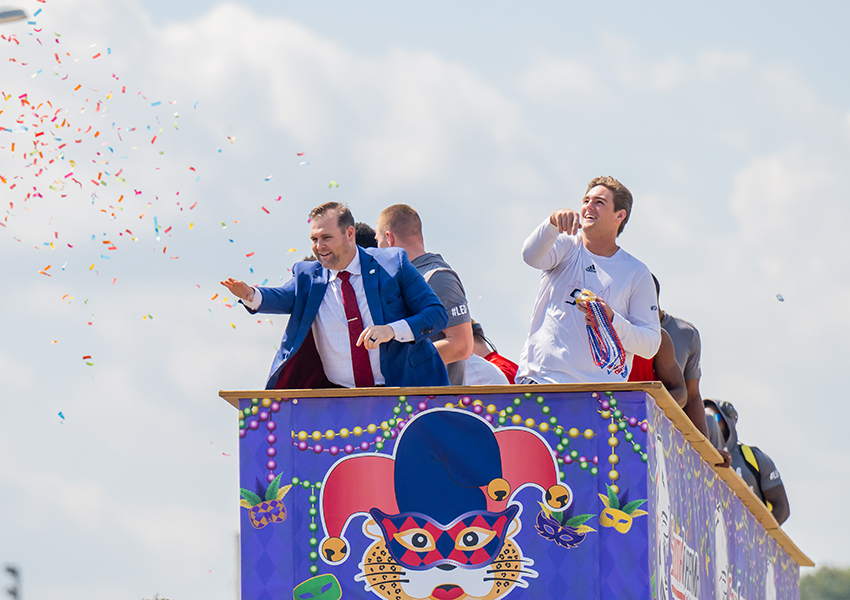 A group of alumni on a float in a parade.