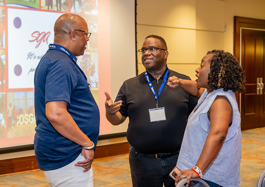 Three alumni discussing South Alabama activities.