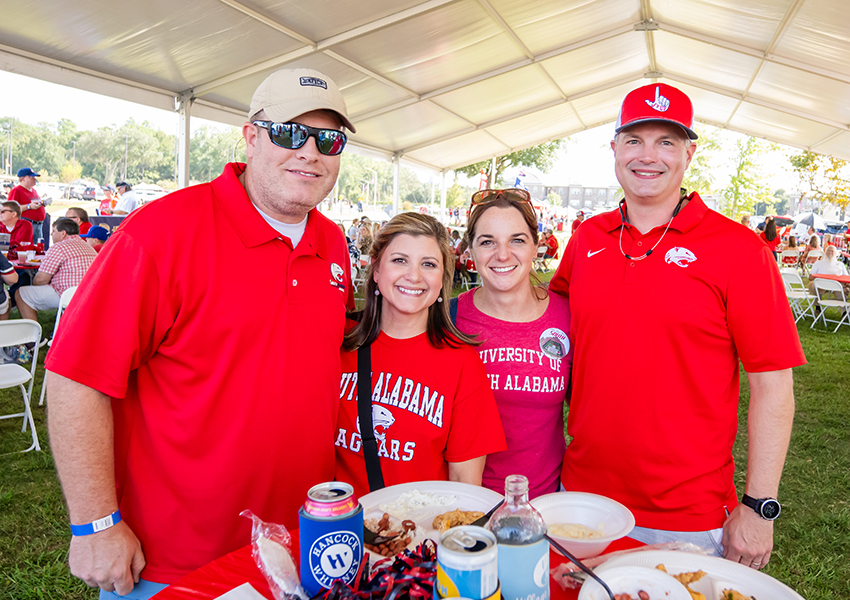 Four alumni smiling.