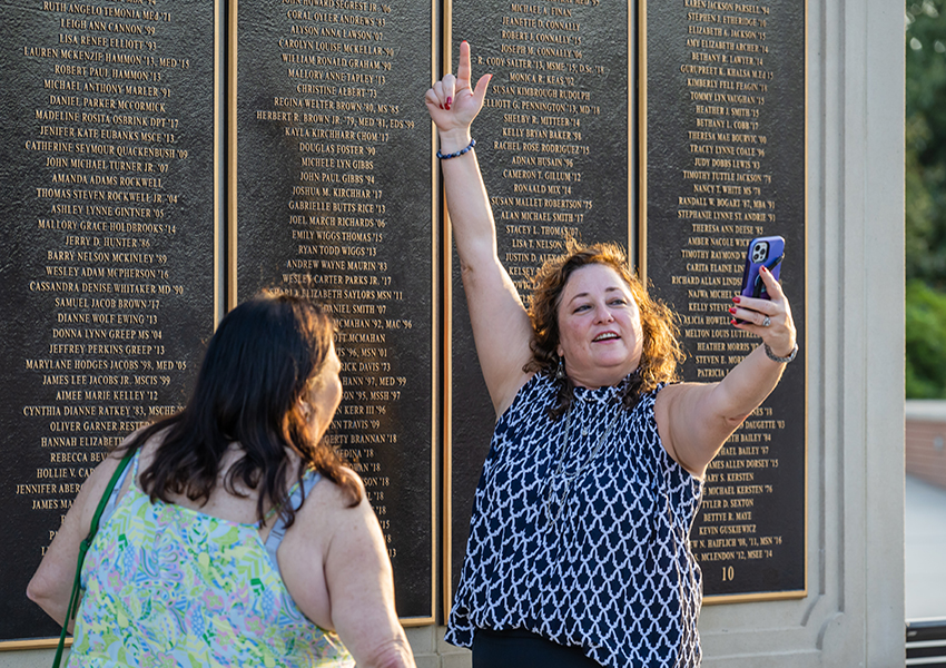 Woman taking a selfie in front of the Wall of Honor.