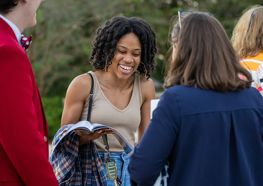 Woman laughing talking to two people at event.