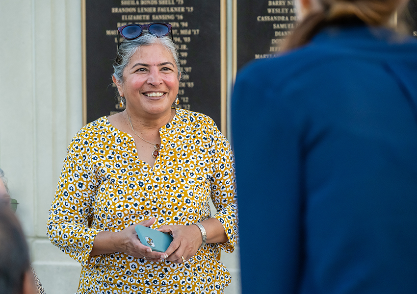 Woman smiling holding phone in front of Wall of Honor.