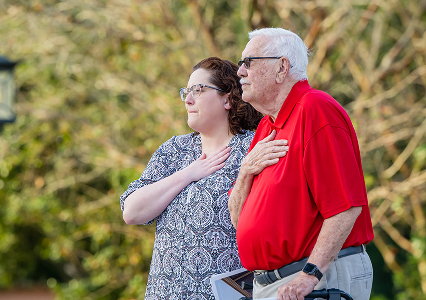 Two people holding hands over heart.