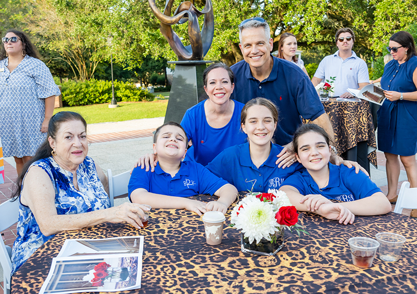 Family with three kids at event sitting at table.