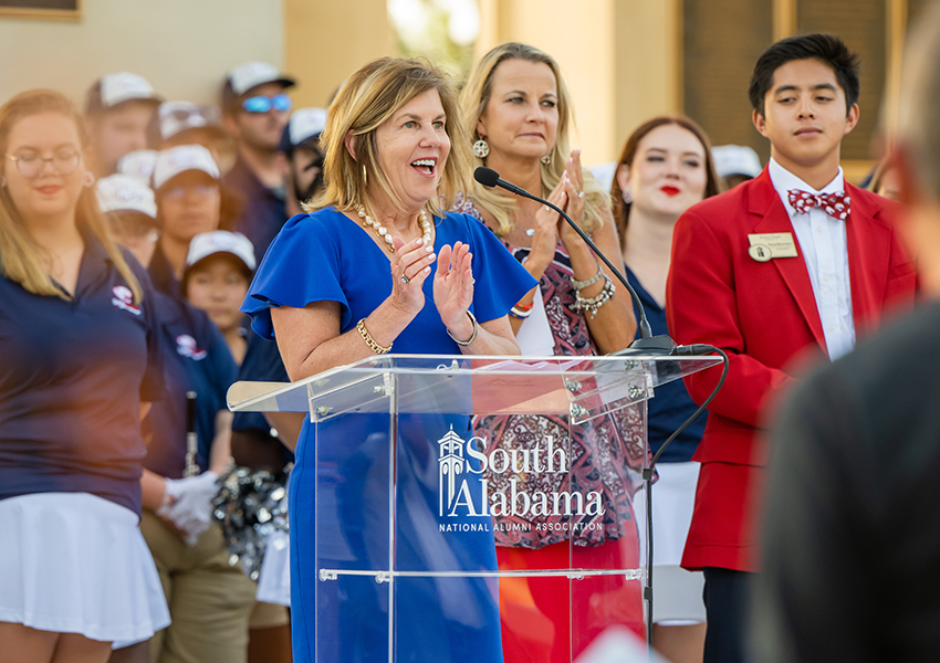 Margaret Sullivan smiling and clapping at podium.