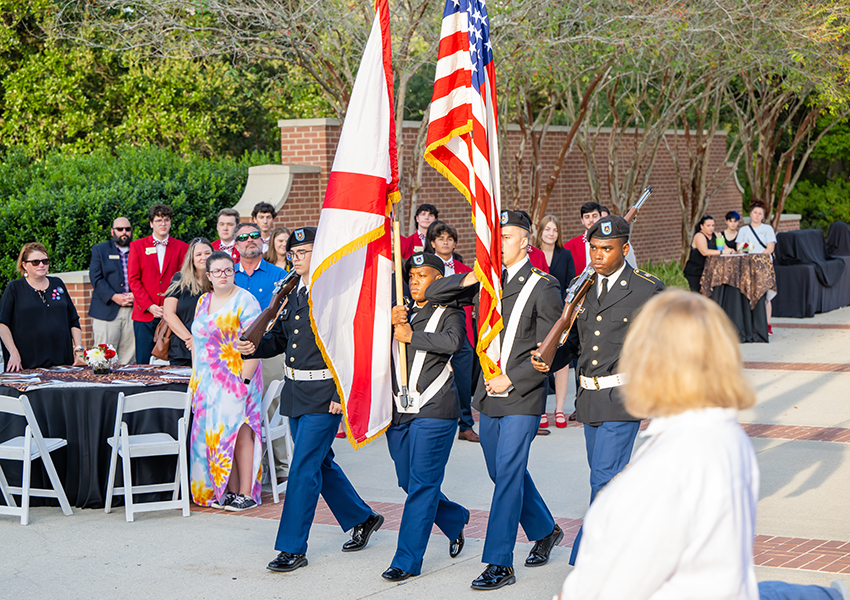 Military members walking carrying flags.