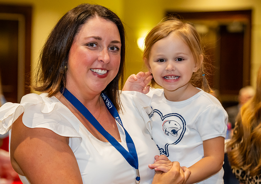 An alumni and a child smiling.