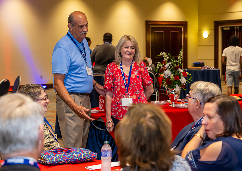 Two alumni discussing to a group of people.