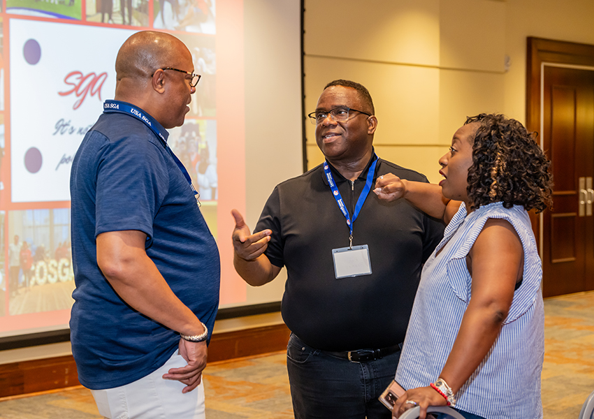 Three alumni discussing South Alabama activities.