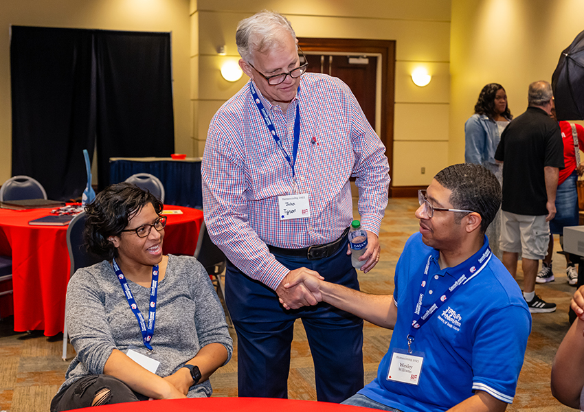 Three alumni greeting each other.